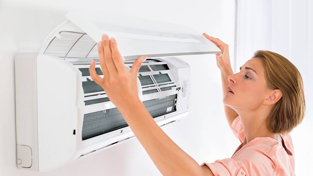 Woman inspecting air conditioner unit.